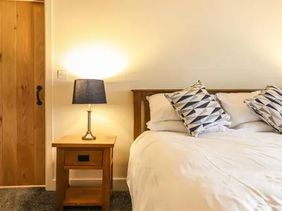 a bedroom with a bed and a table with a lamp at Bodaioch Cottage in Caersws