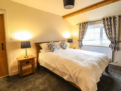 a bedroom with a large bed and a window at Bodaioch Cottage in Caersws
