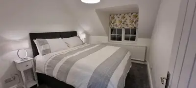 a white bedroom with a bed and a window at Modern and spacious 2 bedroom apartment with free parking in Glyn-Ceiriog