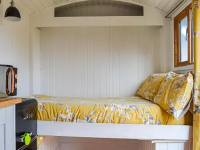 a bed in a tiny house with yellow sheets at Ty Olwyn Bach - Uk36418 in Talybont