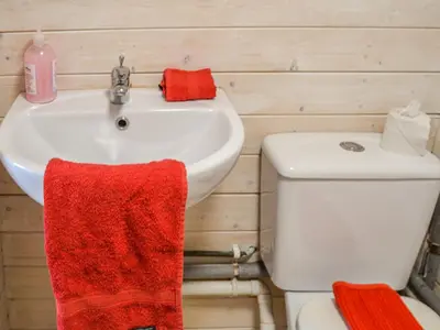 a bathroom with a white sink and a red towel at Ty Bach Twt - Uk36419 in Talybont