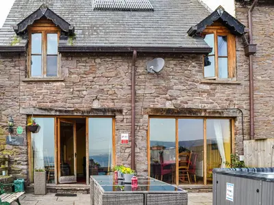 a stone house with glass doors and windows at Peacock Cottage - Uk36422 in Talybont
