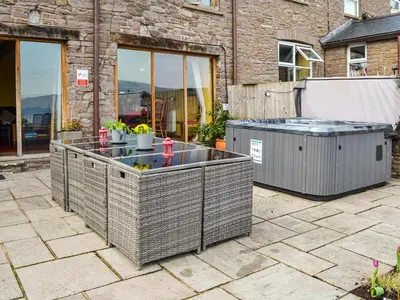 a patio with a hot tub and two trash at Peacock Cottage - Uk36422 in Talybont
