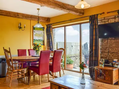 a dining room with a table and chairs and a large window at Peacock Cottage - Uk36422 in Talybont