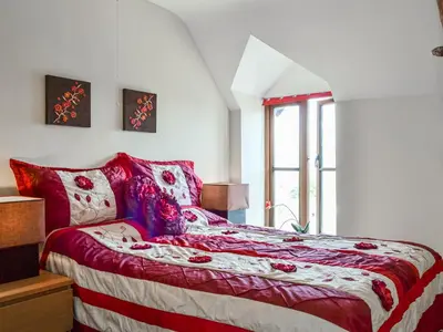 a bedroom with a red and white bed with a window at Peacock Cottage - Uk36422 in Talybont