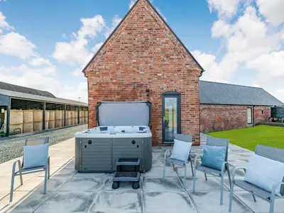 a patio with chairs and a grill in front of a brick building at Buckley Farm, Barn 1 - Uk36588 in Oswestry