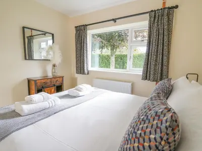 a bedroom with a large white bed and a window at Ger Yr Afon Cottage in Rhayader