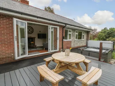 a wooden table and two benches on a deck at Ger Yr Afon Cottage in Rhayader