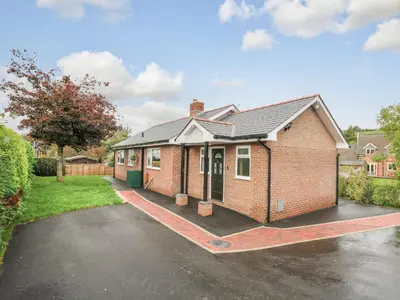 a red brick house with a parking lot at Ger Yr Afon Cottage in Rhayader