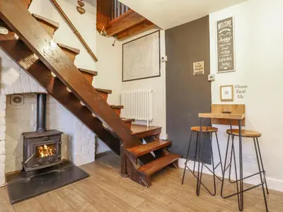a living room with a staircase and a wood stove at Pengeulan in Machynlleth