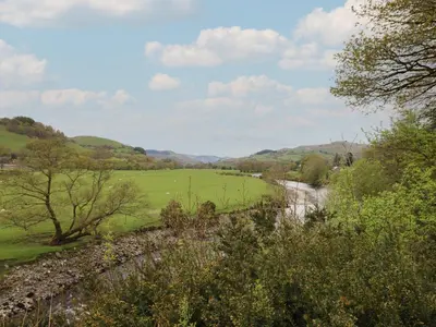 a view of a field with a river and trees at Pengeulan in Machynlleth