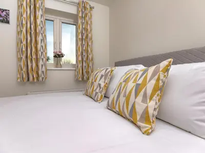 a bed with yellow and white pillows and a window at 2 Bedroom Home Near the Heart of Ludlow - Pass the Keys in Ludlow
