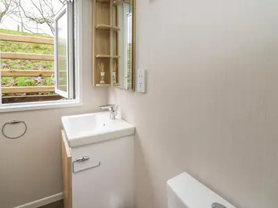 a white bathroom with a sink and a window at The Fox Den in Rhayader