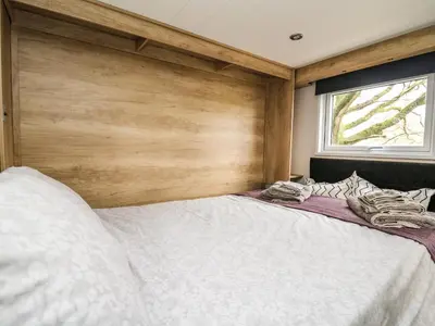 a bedroom with a large bed with a wooden wall at Meadow Retreat in Rhayader