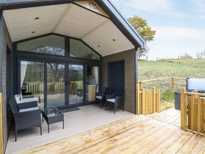 a screened in deck with chairs and tables at Meadow Retreat in Rhayader