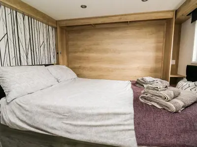 a bedroom with a large bed with a wooden headboard at Hillside Lodge in Rhayader