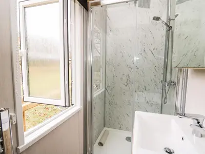 a bathroom with a shower and a sink and a window at Hillside Lodge in Rhayader