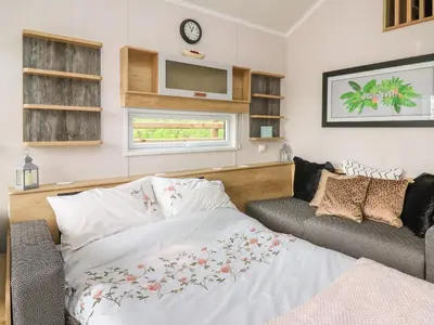 a bedroom with a bed and a couch and a tv at Woodland Escape in Rhayader