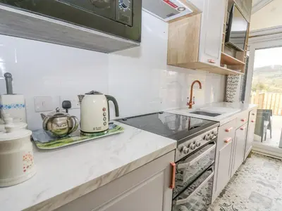 a kitchen with white cabinets and a stove top oven at Hares Rest in Rhayader