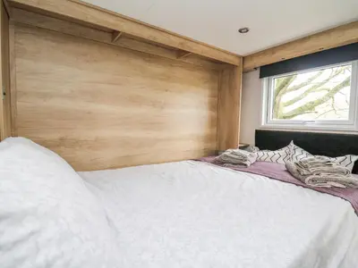 a bedroom with a large white bed with a wooden wall at Hares Rest in Rhayader
