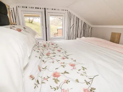 a bedroom with a white bed with pink flowers on it at Hares Rest in Rhayader