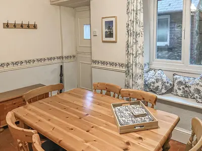 a dining room with a wooden table and chairs at New Cottage in Penmaenpool