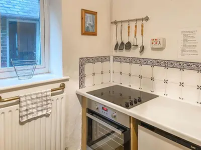 a kitchen with a stove top oven next to a window at New Cottage in Penmaenpool