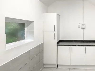 a white kitchen with white cabinets and a window at New Cottage in Penmaenpool