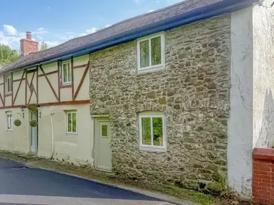 an old stone house with green doors and windows at Bodeinion in Llanfair Caereinion
