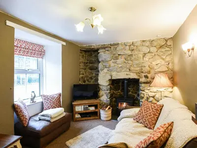 a living room with a stone fireplace and a couch at Glasfor in Llwyngwril
