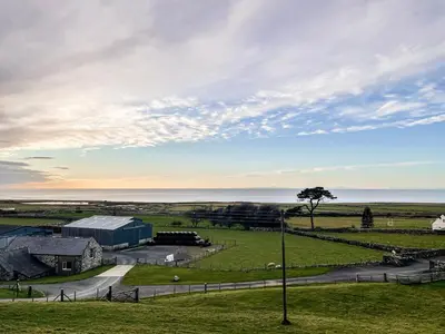 a view of a farm with the ocean in the background at Glasfor in Llwyngwril