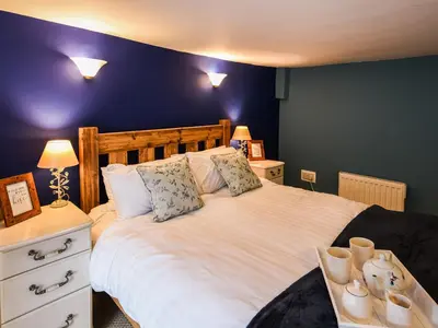 a bedroom with a large white bed with blue walls at Glasfor in Llwyngwril