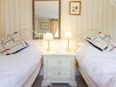 a bedroom with two beds and a night stand with two lamps at Neuadd Wen in Derwen