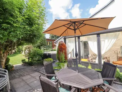 a table and chairs with an umbrella on a patio at Neuadd Wen in Derwen