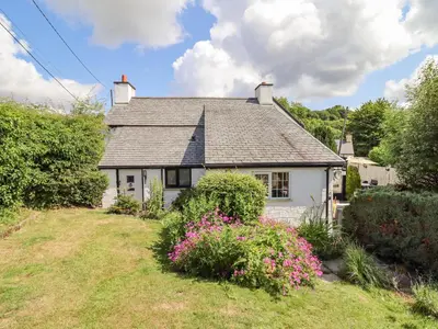 a small white house with flowers in the yard at Neuadd Wen in Derwen