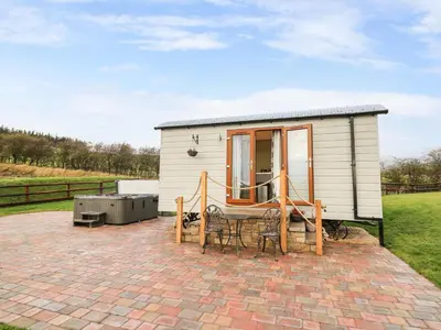a small white tiny house with a patio at Highland View in Rhayader