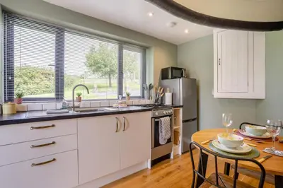 a kitchen with white cabinets and a table with chairs at 1 Bed in Aberaeron oc-bow300 in Henfynyw Upper