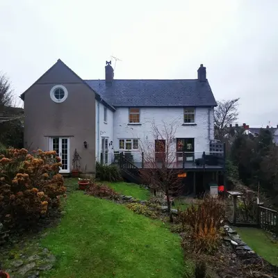 a white house with a yard in front of it at Rooms by the River at Glan Aber in Cynwyd