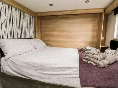 a bedroom with a large bed with a wooden headboard at Oak Tree View in Rhayader