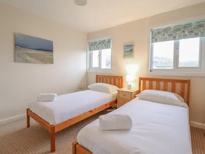 two beds in a room with two windows at 48 Glan Y Mor in Fairbourne