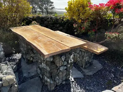 a wooden bench sitting on top of a stone wall at Bwthyn Nain Cottage near Harlech with ocean views in Llanfair