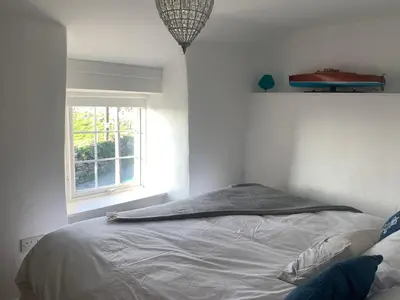 a bed in a white room with a window at Bwthyn Nain Cottage near Harlech with ocean views in Llanfair