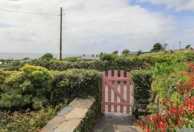 a pink gate in a garden with flowers at Bwthyn Nain Cottage near Harlech with ocean views in Llanfair