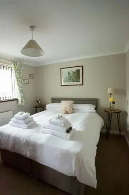 a bedroom with a white bed with towels on it at Goitre Bach Cottage in Aberaeron