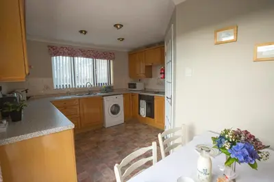 a kitchen with a table and a sink and a washing machine at Goitre Bach Cottage in Aberaeron