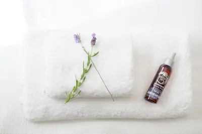 a flower sitting on top of a towel with a bottle of soap at Pant-Y-Celyn Studio Apartment in Aberaeron