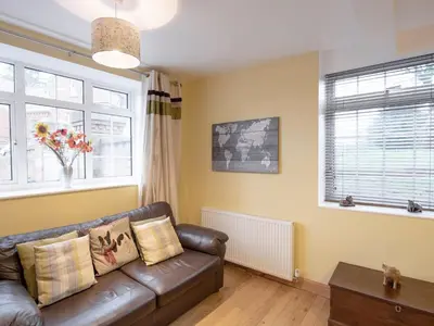 a living room with a leather couch and two windows at The Coach House in Oswestry