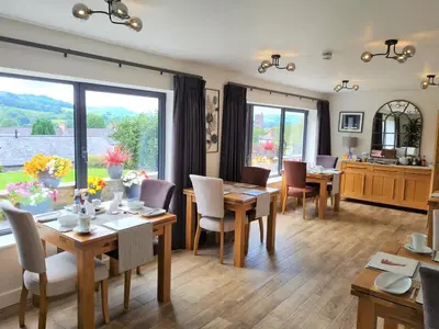 a dining room with tables and chairs and a large window at Camden Lodge B&B and Cottage Brecon in Brecon