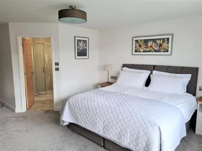 a bedroom with a large bed with white sheets at Camden Lodge B&B and Cottage Brecon in Brecon