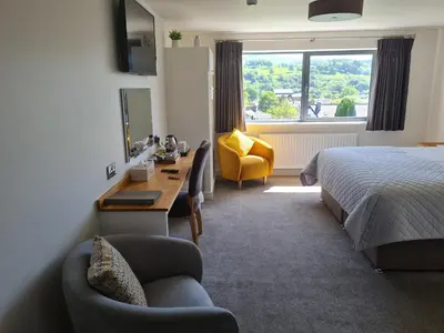 a hotel room with a bed and a desk and a chair at Camden Lodge B&B and Cottage Brecon in Brecon